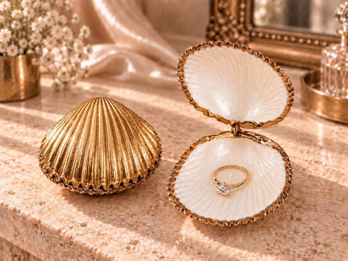 Handmade hinged cockle shell ring box with a natural white ridged interior and hand-finished gold-leaf edging. Available with a natural or gold-leaf outer shell, a natural or gold-speckled interior, and with no pearl or one pearl ring stop. A coastal jewellery box for storing rings and small treasured pieces.