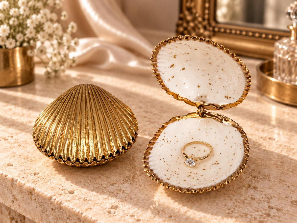 Handmade hinged cockle shell ring box with a natural white ridged interior and hand-finished gold-leaf edging. Available with a natural or gold-leaf outer shell, a natural or gold-speckled interior, and with no pearl or one pearl ring stop. A coastal jewellery box for storing rings and small treasured pieces.