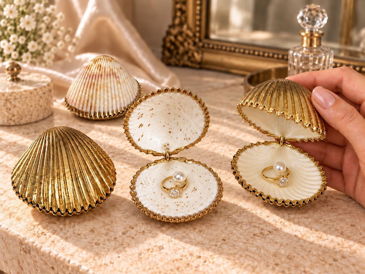 Handmade hinged cockle shell ring box with a natural white ridged interior and hand-finished gold-leaf edging. Available with a natural or gold-leaf outer shell, a natural or gold-speckled interior, and with no pearl or one pearl ring stop. A coastal jewellery box for storing rings and small treasured pieces.