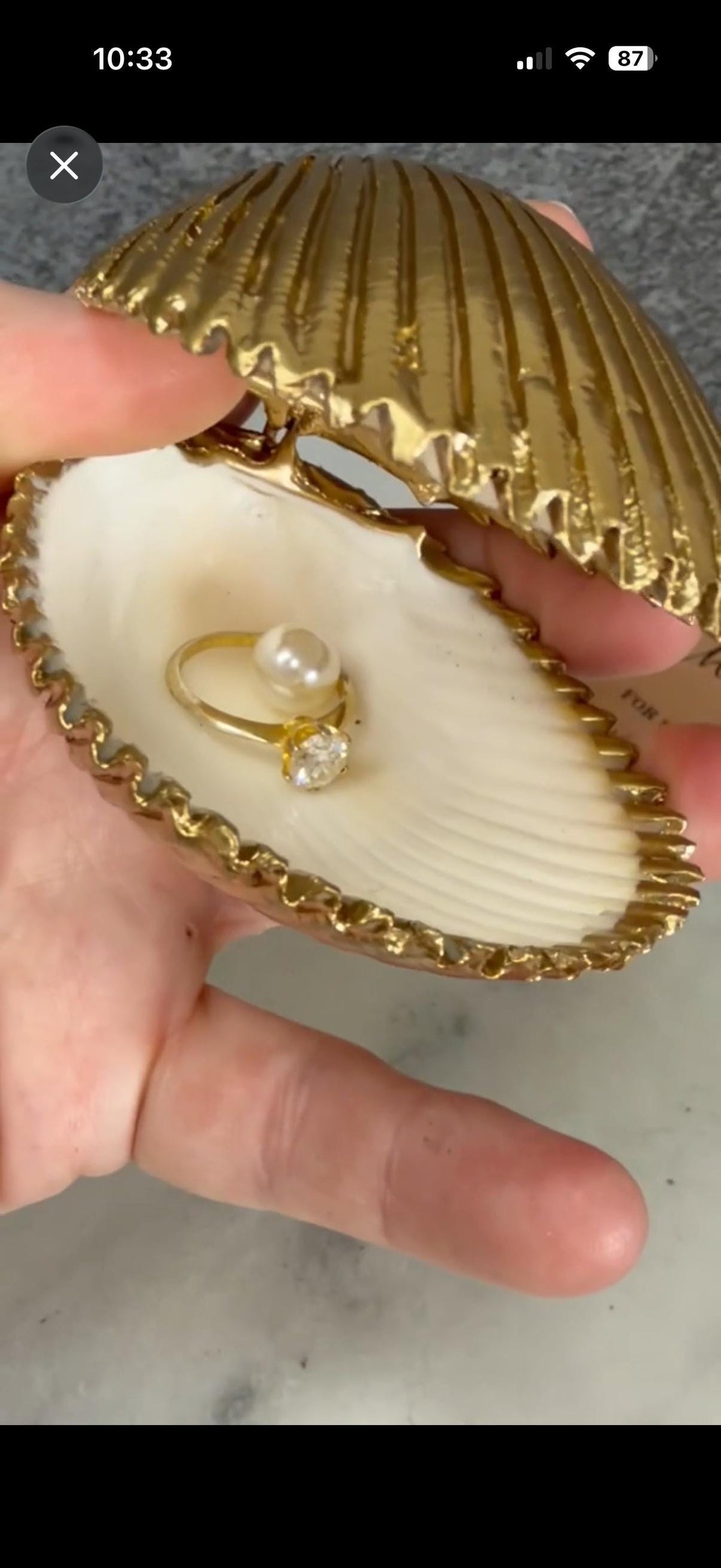 Handmade hinged cockle shell ring box with a natural white ridged interior and hand-finished gold-leaf edging. Available with a natural or gold-leaf outer shell, a natural or gold-speckled interior, and with no pearl or one pearl ring stop. A coastal jewellery box for storing rings and small treasured pieces.
