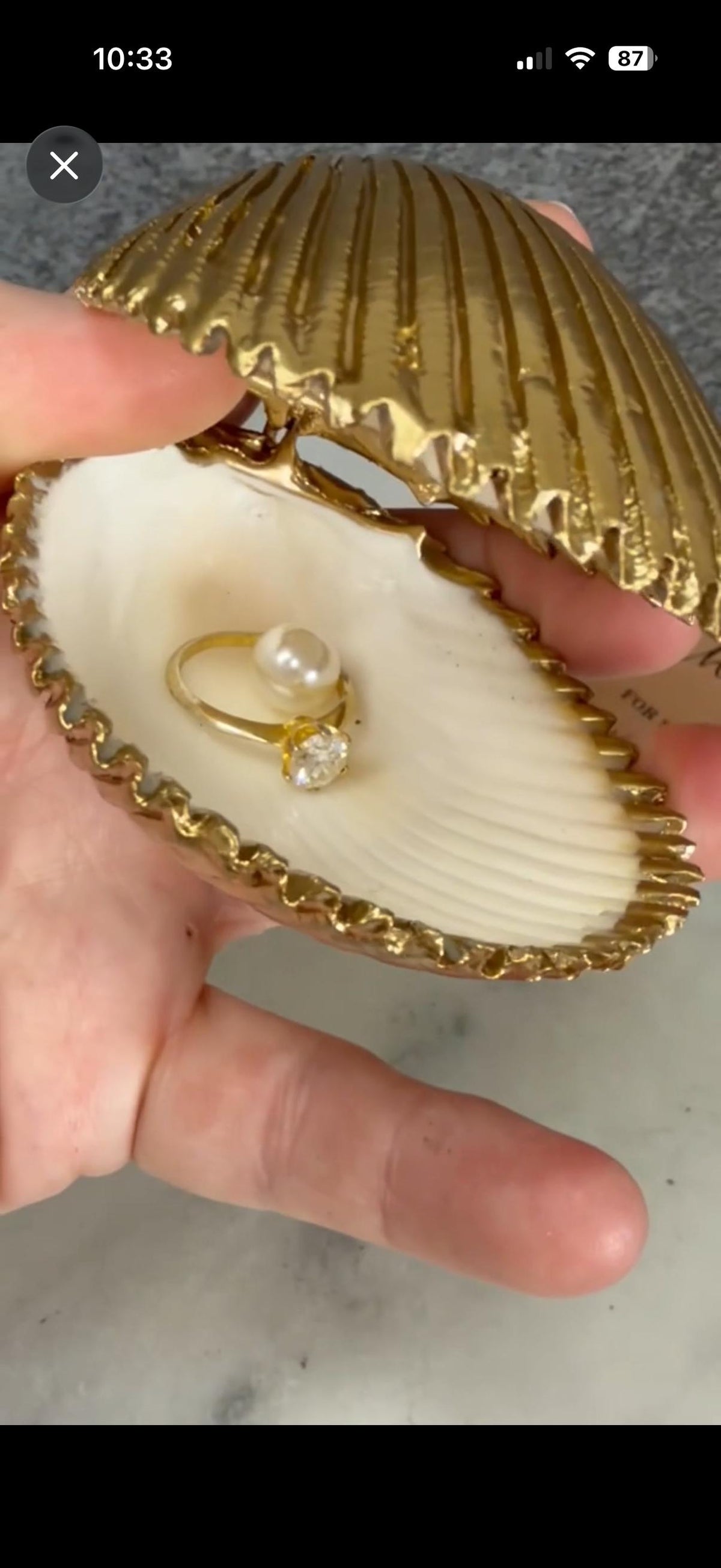 Handmade hinged cockle shell ring box with a natural white ridged interior and hand-finished gold-leaf edging. Available with a natural or gold-leaf outer shell, a natural or gold-speckled interior, and with no pearl or one pearl ring stop. A coastal jewellery box for storing rings and small treasured pieces.